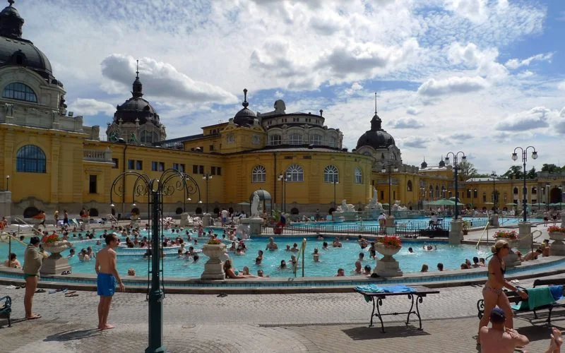 Outdoor pools and yellow bathhouse at Széchenyi baths in Budapest